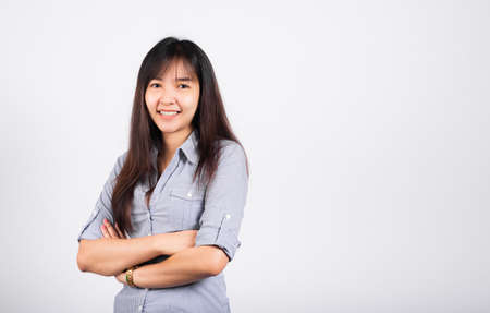 Woman standing her smile confidence with crossed arms isolated white background, Asian happy portrait beautiful young Thai female looking to camera in studio shot on white background and copy spaceの写真素材