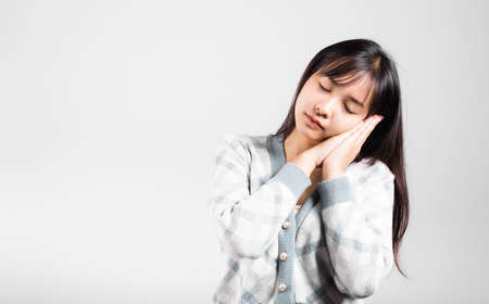Sleep woman pretended emotions sleeping tired eyes closed dreaming with hands together near face, Portrait Asian beautiful young female sleep studio shot isolated on white background with copy spaceの写真素材
