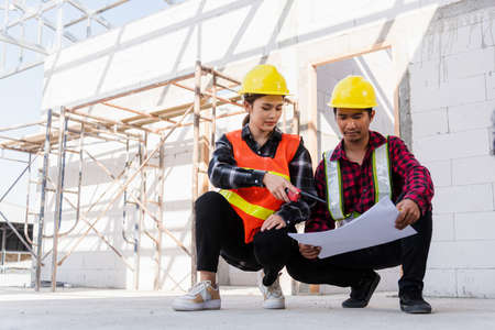 Architect and client discussing help create plan with blueprint of the building at construction...