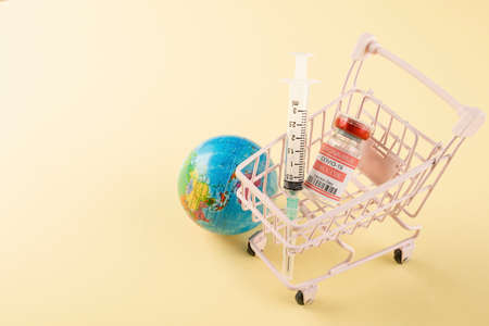 Shopping cart with vaccine vials bottles and syringes for vaccination against coronavirus, medicine...