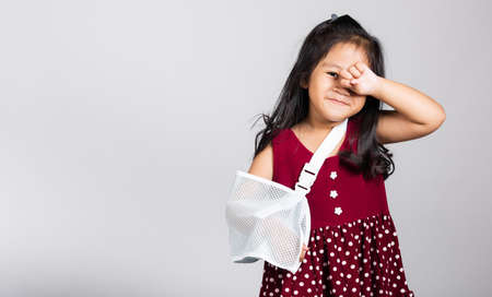 Arm broken. Little cute kid girl 3-4 years old hand bone broken from accident with arm splint in studio shot isolated on white background, Asian children preschool injured after accident, health conceptの写真素材
