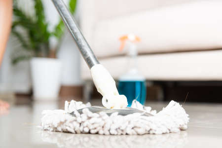 Asian woman washes the floor with a mop and rag indoors, housewife washing floor mopping at home in...
