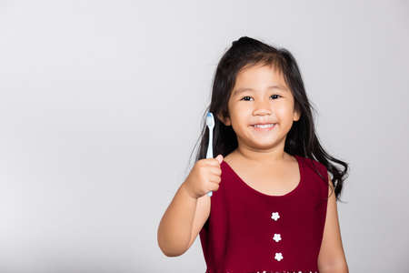 Little cute kid girl 3-4 years old show brush teeth and smile in studio shot isolated on white...