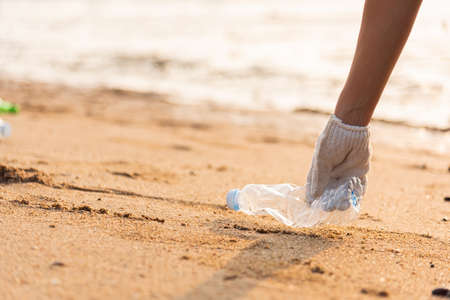 Volunteer woman picking plastic bottle into trash plastic bag black for cleaning the beach, female clean up garbage, Ecology concept and World Environment Day, Save earth conceptの写真素材