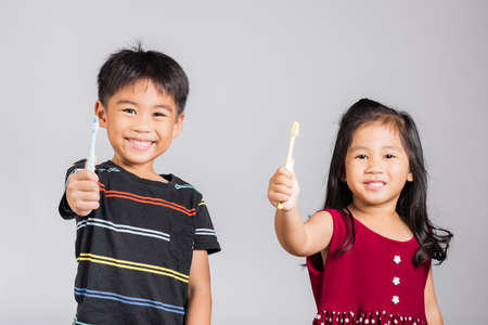 Little cute kid boy and girl 3-6 years old show brush teeth and smile in studio shot isolated on white background, Asian children holding toothbrush in mouth by himself, Dental hygiene healthy conceptの写真素材