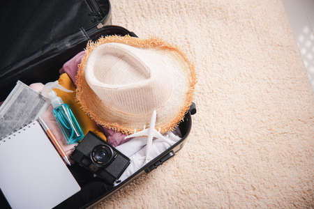 Open suitcase with traveler belongings clothes and accessories of things ready packing to be taken on summer holiday, Travel vacation luggage preparations concept, top viewの写真素材