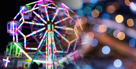 Blurry rollercoaster in bokeh, Ferris wheel at night of colorful with outdoor, Defocused (blurred) and blur image of Amusement park, The annual temple event has activities. Image out of focusの写真素材