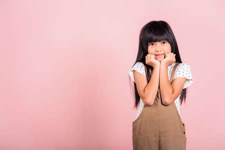 Asian little kid 10 years old hands touch chin thinking dream at studio shot isolated on pink...