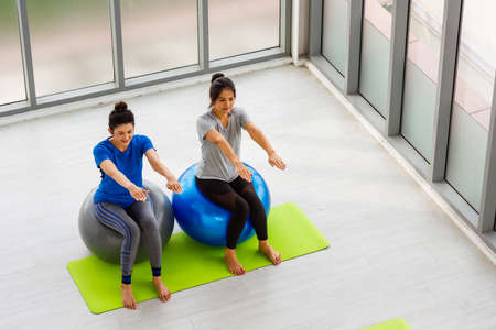 Above two Asian adult and young woman in sportswear doing aerobics yoga exercise with sitting on...