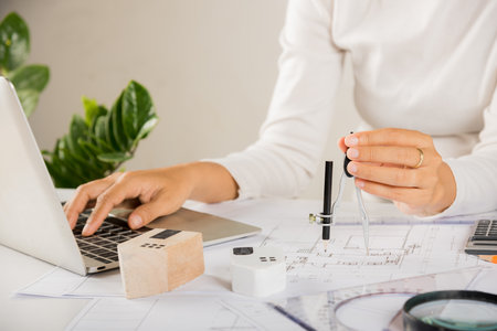 Architectural project workplace. Architect typing laptop keyboard to review design of house building...
