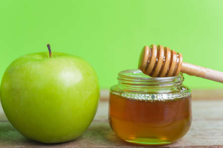 Jewish holiday, Apple Rosh Hashanah, on the photo have honey in jar and green apples on wooden with green backgroundの写真素材
