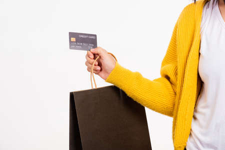 Happy woman hand she wears yellow shirt holding black shopping bags and credit card, young female...