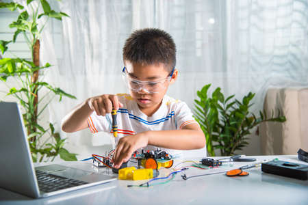Little child tighten the nut with a screwdriver to assemble car toy, Asian kid boy assembling the...
