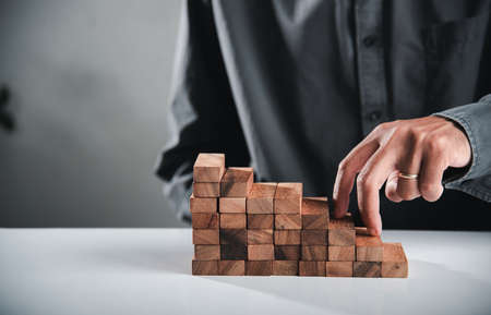 Business two finger symbol walking up on wood blocks shape staircase to climb up career ladder step up stair growth success, prevent collapse or crash conceptの写真素材