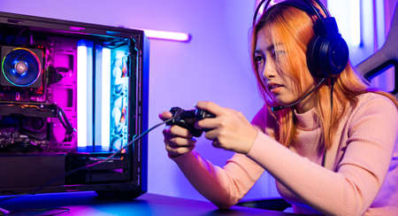 Gamer using joystick controller for virtual tournament plays online video game with computer neon...