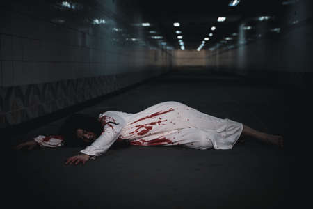 The girl was hit by a car and lying died on the road. full of blood left unattended, Horror bloodthirsty woman ghost horror she death and scary at night in tunnel, Happy halloween day conceptの写真素材