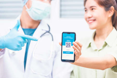 Asian young woman in medical mask show app smartphone mobile digital screen vaccinated coronavirus...