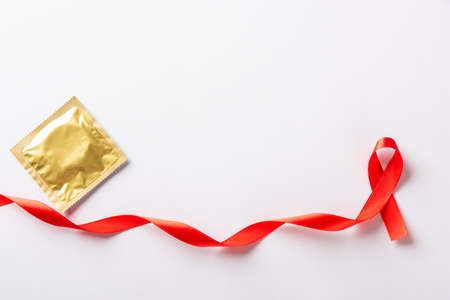 Red bow ribbon symbol HIV, AIDS cancer awareness and condom with shadows, studio shot isolated on white background, Healthcare medicine sexually concept, World AIDS Dayの写真素材