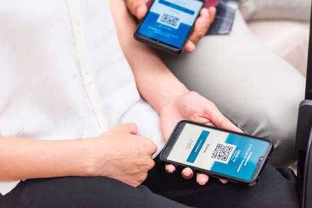 Vaccination passport, Traveler woman holding health passport of vaccination certification on smartphone app at airport for travel during coronavirus pandemic, Mobile app of virus covid-19の写真素材