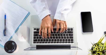 Nurse working using computer browsing internet, Closeup hands female doctor wear uniform in hospital she typing information on keyboard laptop, Healthcare medical health website technology online dataの写真素材