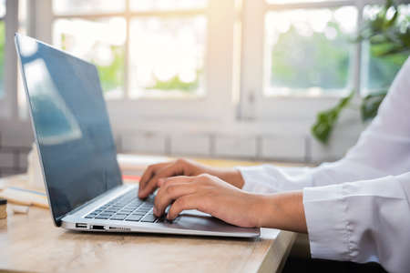 Back to school. Close up hands of female using computer sitting at school table, Young woman teacher...