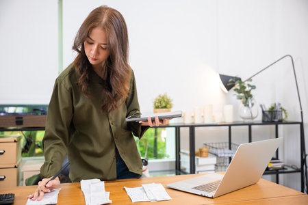 Asian female calculating family budget financial and accounting at home, young woman working with...