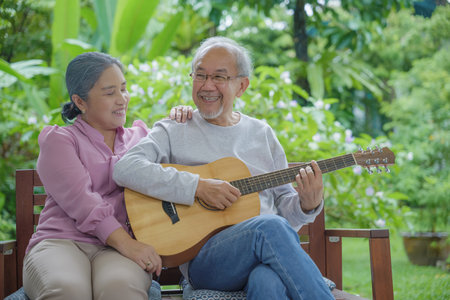 Happy Asian senior couple elderly man playing guitar while his wife singing together outdoors at home, Activity family health care, Enjoying lifestyle during retirement life having fun of senior olderの写真素材