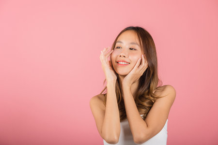 Femininity. Asian beautiful young woman smiling mask cosmetic patches gel under the eyes, Portrait female touching clean skin medical hydrogel eye patch on face, isolated on pink background, skincareの写真素材