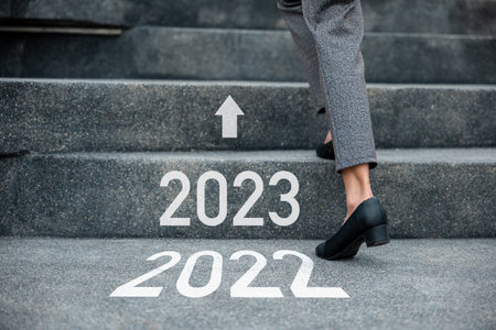 Happy new year 2023. Stepping going up stairs in city, Closeup legs of businesswoman hurry up walking on stairway from 2022 to 2023, foot of business woman wear black shoes step up success next yearsの写真素材