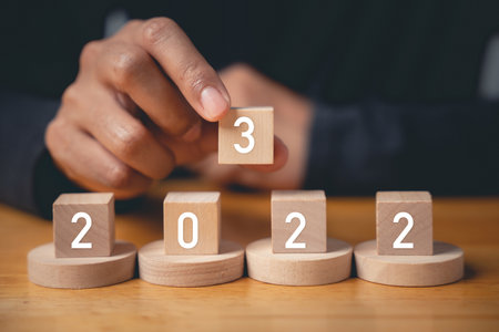 Happy New Year 2023. Happy businessman hand holding number 3 on wooden block to put replace or...