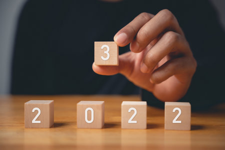 Happy New Year 2023. Happy businessman hand holding number 3 on wooden block to put replace or...
