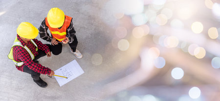 Architect and client discuss help create plan with blueprint of the building at construction site floor. Asian engineer foreman worker man and woman meeting talking on drawing paper project, top viewの写真素材