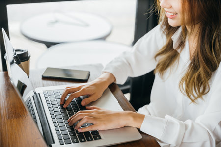 Asian young business woman lifestyle using laptop computer at cafe coffee shop, Happy beautiful freelancer typing keyboard on laptop, working online outside officeの写真素材