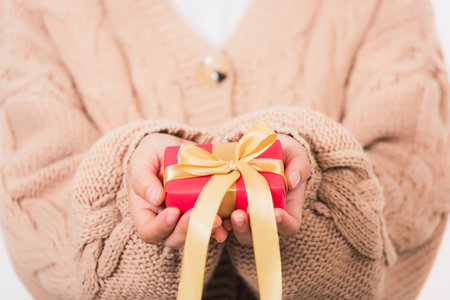 Valentine Day. Woman beauty hands holding small gift package box present wrapped paper with ribbon, Christmas, New year, Birthday holiday background conceptの写真素材