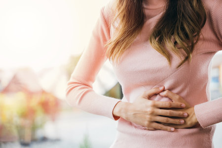 Asian young female suffers from stomachache after eating spoiled food, Abdominal pain from menstrual cramps, Sick woman unhappy having stomach ache digestive problem at homeの写真素材