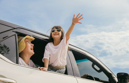 Happy family day. Asian mother father and children smiling sitting in compact white car looking out windows, Summer at the beach, Car insurance, Family holiday vacation travel, road trip conceptの写真素材