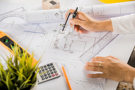 Architectural project workplace. Architect drawing with divider compass on house plan blueprint...