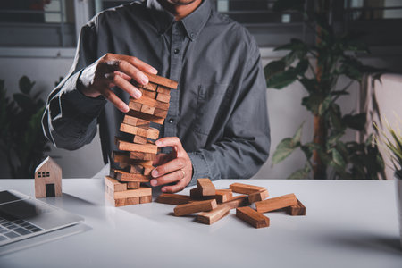 Business fail danger building tower challenge game building. Businessman hand pulling out wood block and failed the tower is falling down he wrong strategy decisionの写真素材