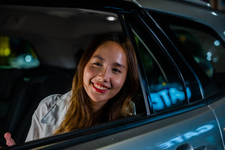 Asian businesswoman working late commuting from office in Taxi backseat with mobile phone in city at...