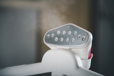 Close up of electric hand steam generator while its hot on the ironing board place for clothes at...