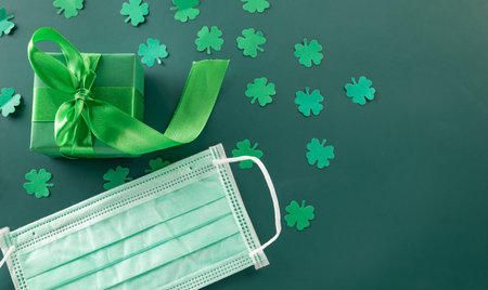 Top View flat lay of paper cut clover leaves festive decor and Medical face mask, shamrocks leaf...