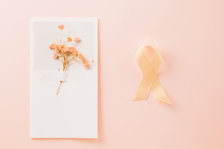 Pink awareness ribbon sign and paper card flower of World Cancer Day on pink background with copy space, concept of medical and health care support, Breast cancer awareness concept, 4 Februaryの写真素材