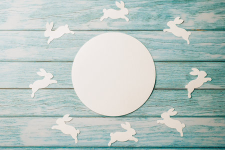 Easter Day Concept. Top view holiday banner background web design white circle paper circle space for text and bunny rabbit on blue wood background with copy space, celebration greeting card, overheadの写真素材