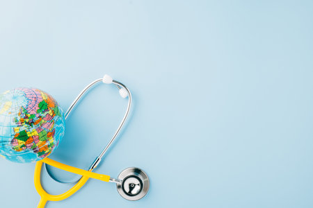 World Health Day. Top view yellow doctor stethoscope wrapped around world globe isolated on pastel blue background with copy space for text, Global healthcare, Health care and medical conceptの写真素材