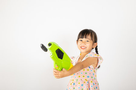 Happy Songkran Day, Asian little girl holding plastic water gun, Thai child funny hold toy water pistol and smile, isolated on white background, Thailand Songkran festival national culture conceptの写真素材