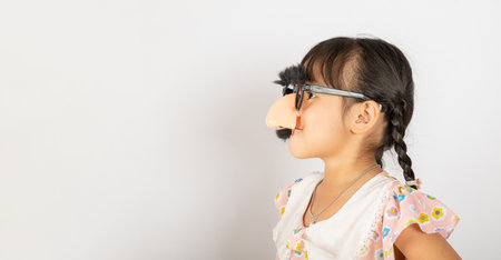 April Fools Day. Portrait of Funny kid little girl clown wears a big nos and glasses and has a...