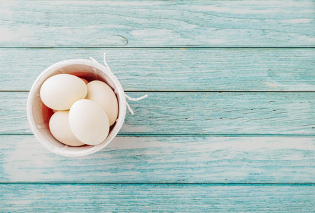 Happy Easter Day Concept. Top view of holiday banner background design white easter eggs and basket on blue wooden background with empty copy space, celebration greeting cardの写真素材