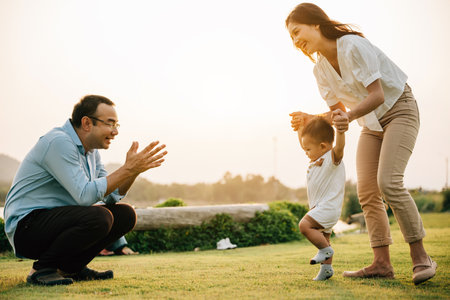 Portrait of a loving family spending quality time in nature, teaching their baby girl to walk on a beautiful spring day. childhood parent care support conceptの写真素材