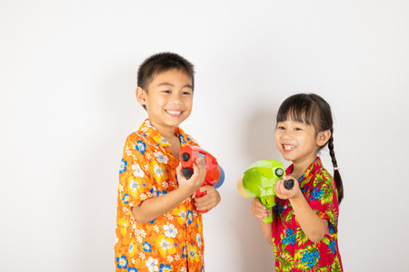 Happy Songkran Day, Asian kid girl and boy holding plastic water gun, Thai child funny smiling hold toy water pistol, isolated on white background, Thailand Songkran festival national culture conceptの写真素材