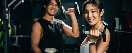 Portrait female athlete in black workout clothes, man and woman holding a dumbbell and smiling cheerfully, works hard to build her strength and shape for a healthy body. lifestyle fitness conceptの写真素材